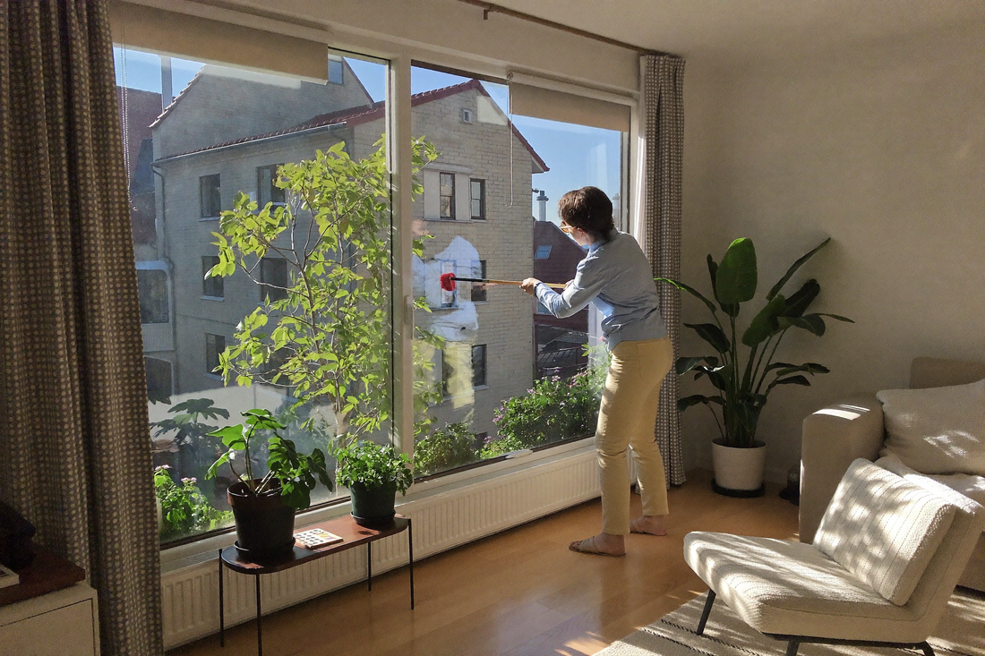Kvinde gør vindue rent i lyst skandinavisk hjem