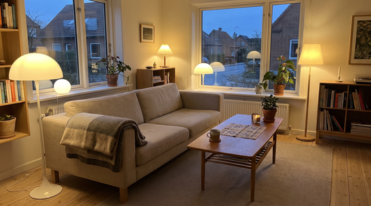 Lys dansk stue med ryddeligt laminatgulv og aftenlys fra lampe